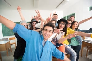 Cheerful classmates posing in classroom in front of a green board
