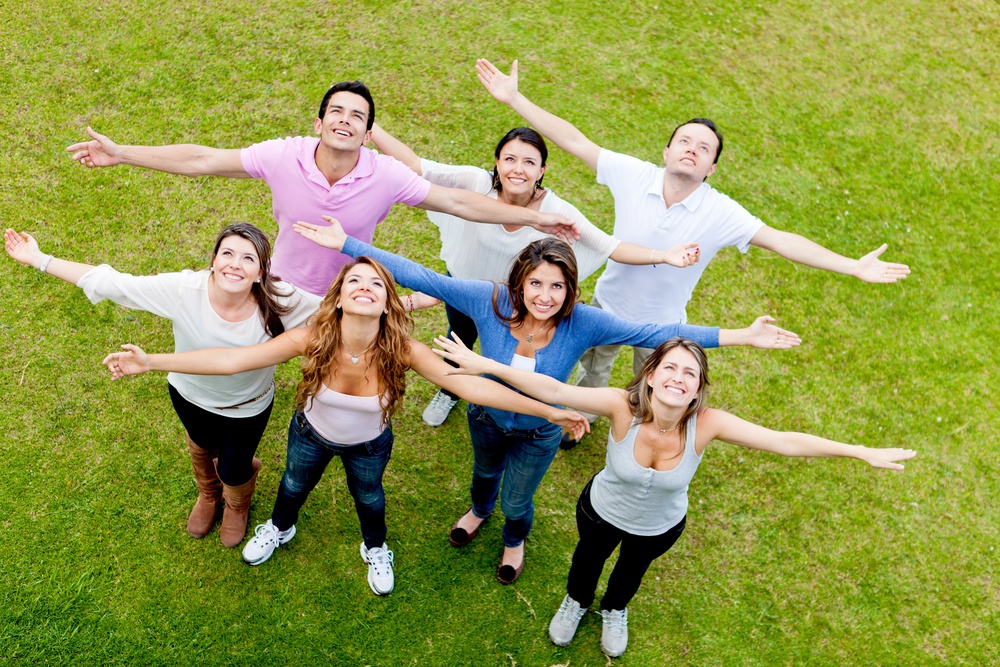 Group of people with open arms outdoors looking up