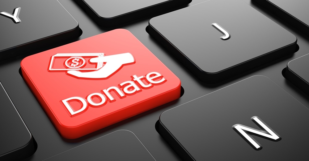 Donate with Money in the Hand Icon - Red Button on Black Computer Keyboard..jpeg