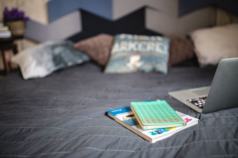 kaboompics_Laptop with books on a bed